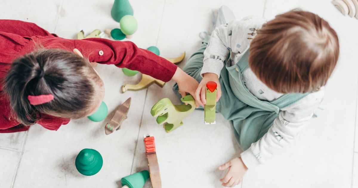 Un moment de jeu au sol avec des jouets en bois, à la maison